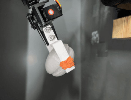 Original project photograph showing rubber bands added to the robotic gripper fingertips.